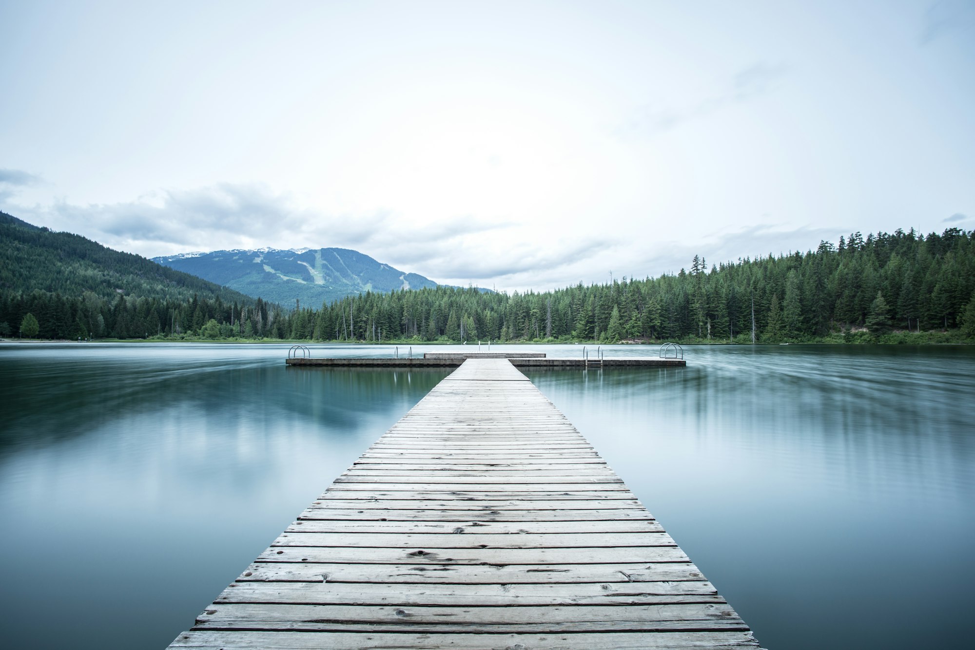 A wooden dock reaching into a still alpine lake