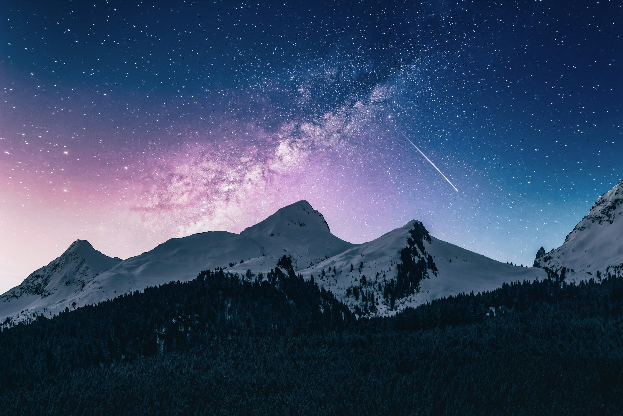 The Milky Way arcing over snowbound peaks at night